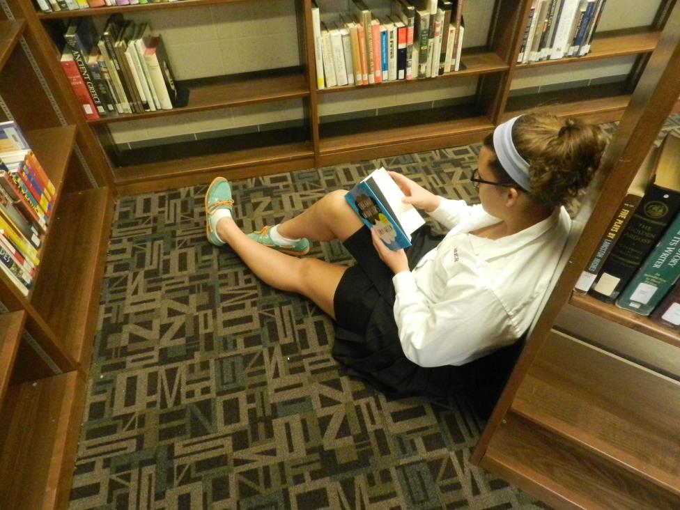 Junior Emily Gates reading The Fault in Our Stars in the Mercy High School media center.