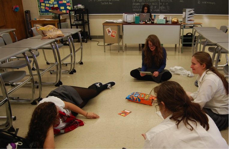 Seniors Meaghan Tilson, Amelia Fanelli, Christina Gee, and Alise Wenner convene for a Dead Poets Society Meeting, reading from a Thanksgiving children's book of poems.