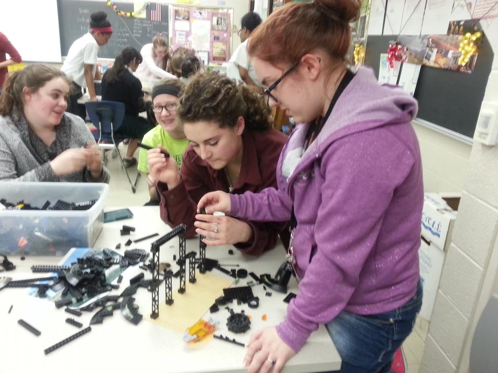 Senior Alise Wenner (sitting down)  and junior Arianna Watson (standing up) work to construct their groups Lego building, using support beams and other Legos, to help give the appearance of a real Roman monument.
